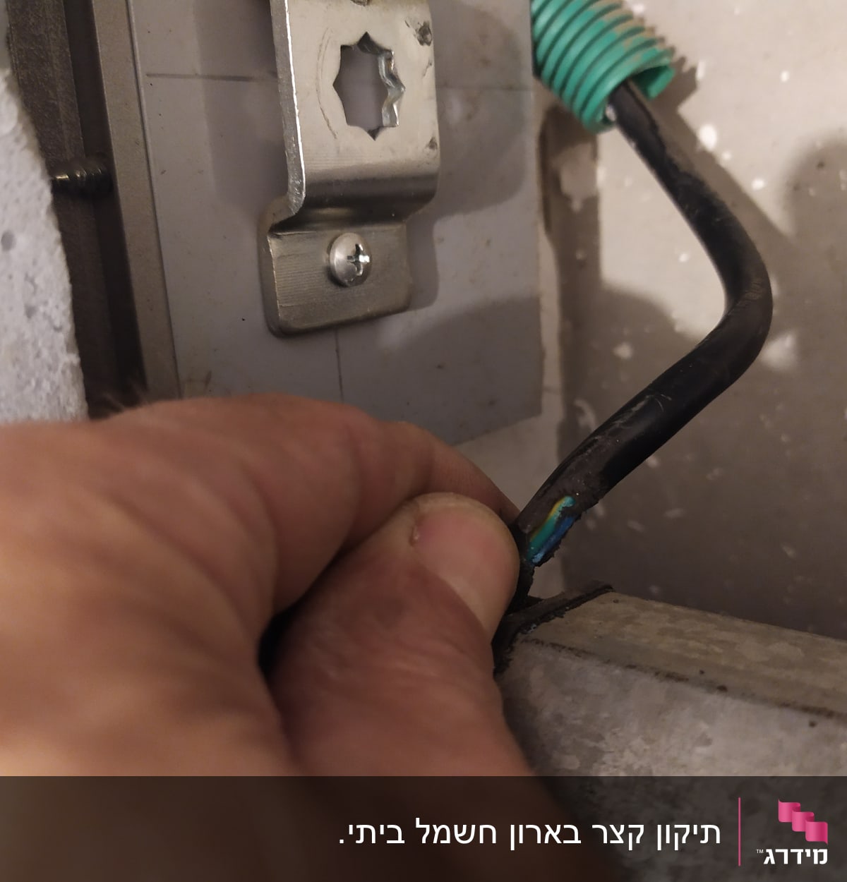 יד מחזיקה חוט חשמל שחור עם בידוד ירוק